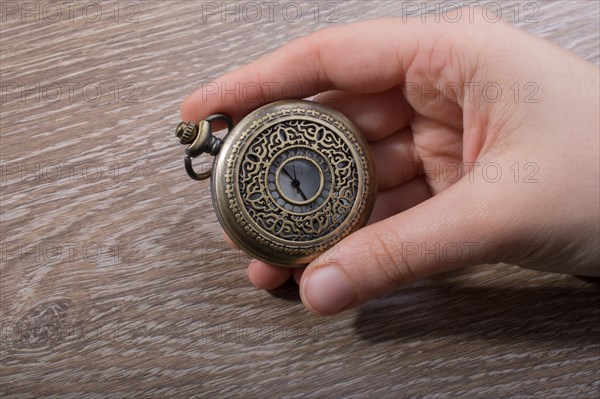 Retro style pocket watch in hand on black background