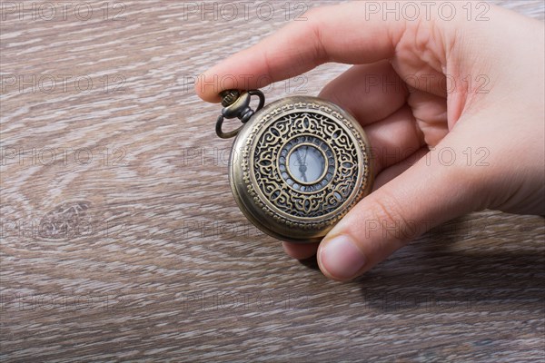 Retro style pocket watch in hand on black background