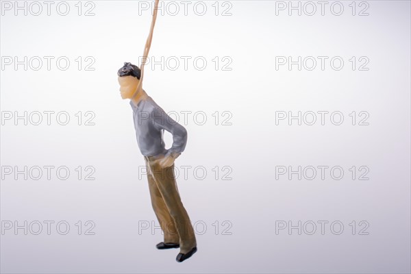 Man figurine tied with aa rope on a brown backgorund