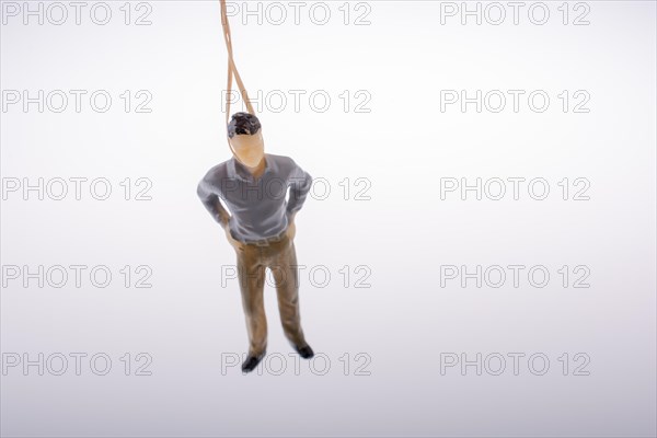 Man figurine tied with aa rope on a brown backgorund