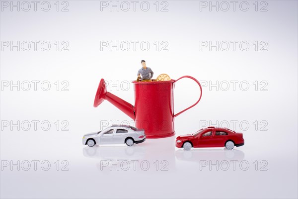 Figurine standing in a watering can with the cars beside