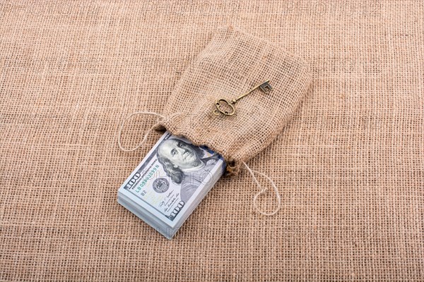 Retro key and bundle of US dollar in a sack on a canvas