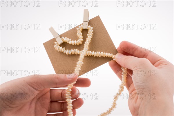 Pearl necklace forms heart shape on paper on white background