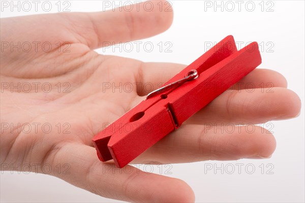 Hand holding a red clothespin on a white background