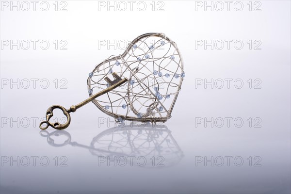 Key and a heart shaped metal cage on white