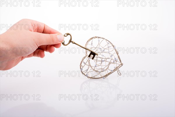 Key and a heart shaped metal cage on white