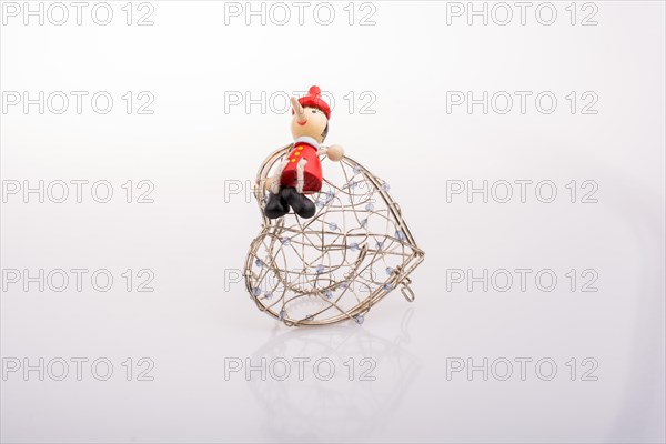 Wooden Pinocchio doll sitting on a heart shaped cage