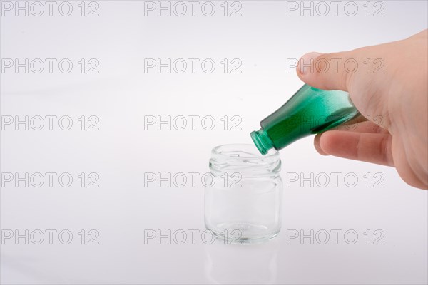 Little colorful bottle over a jar on a white background