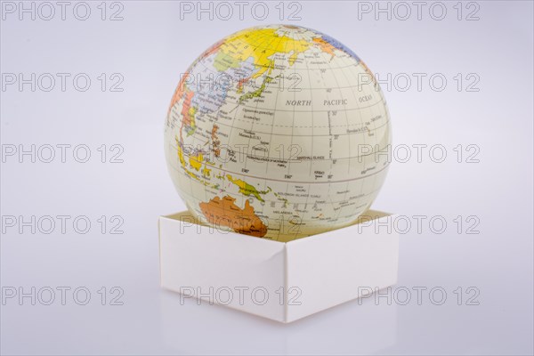 Little model globe put on a white box on a white background