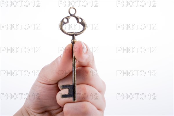 Hand holding a retro styled metal key on a white background