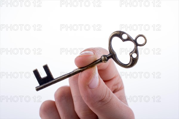 Hand holding a retro styled metal key on a white background