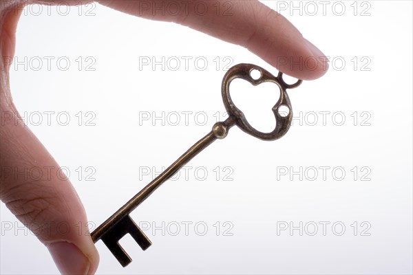 Hand holding a retro styled metal key on a white background