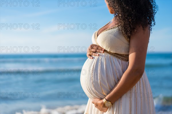 Pregnant maternity latin woman on the beach at sunset