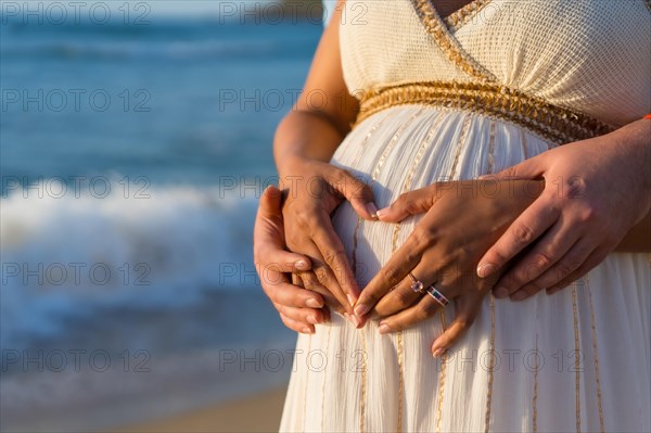 Pregnant maternity latin woman on the beach at sunset
