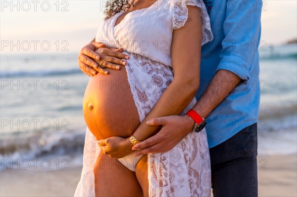 Pregnant maternity latin woman on the beach at sunset