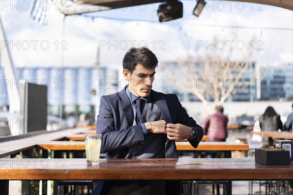 A pensive man looking for his smartphone in his pocket to check something