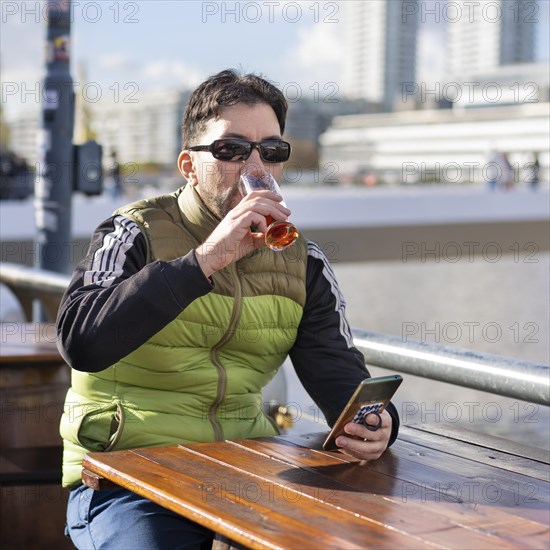 Man drinking a beer while sitting in a bar at the harbor