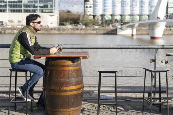 A pensive man looking away while sitting at a bar near the river
