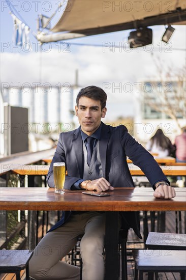Handsome businessman looking at camera e while holding his smartphone