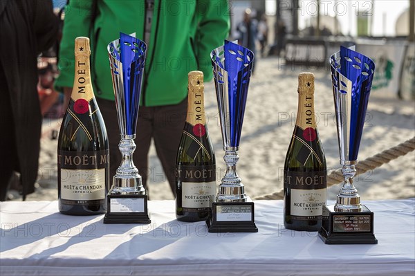 Three champagne bottles and cups stand on a table