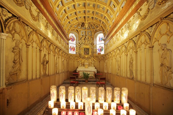 Interior view of a side chapel with figures and candle lights of the Romanesque St-Jean Cathedral