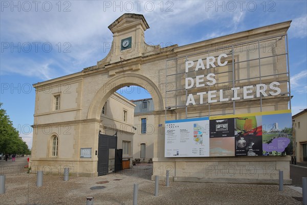 Entrance building with archway and banner to the Parc des Ateliers