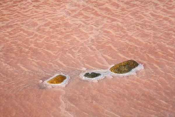 Red salt water with three stones with salt deposit at saline