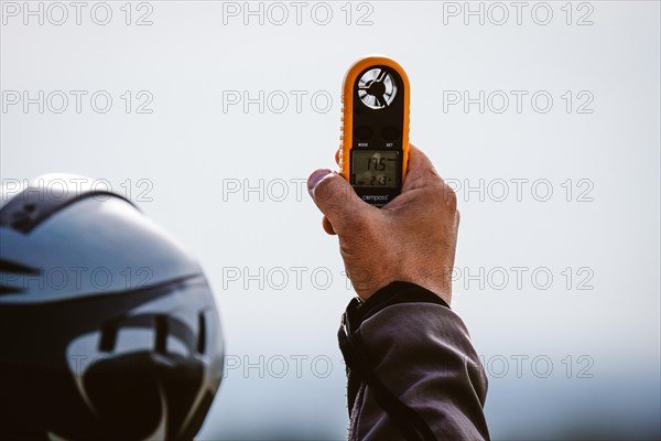 Paraglider pilot with an anemometer in his hand