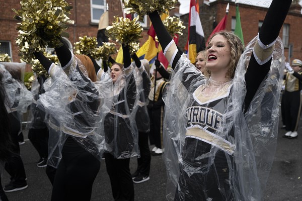 American cheerleaders warm up before the start of the St Patrick's Day parade on a rainy day