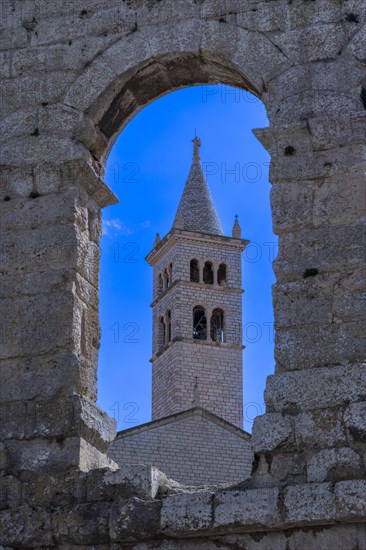 Tower of St Anthony's Church behind an archway from the Roman amphitheatre