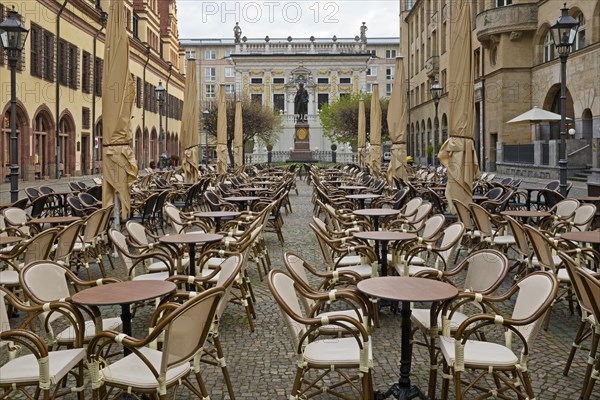 Empty chairs and tables at the Naschmarkt in the early morning with Goethe monument in front of the Old Stock Exchange