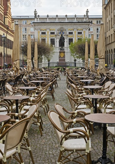 Empty chairs and tables at the Naschmarkt in the early morning with Goethe monument in front of the Old Stock Exchange
