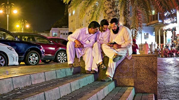 Three men look at mobile phone