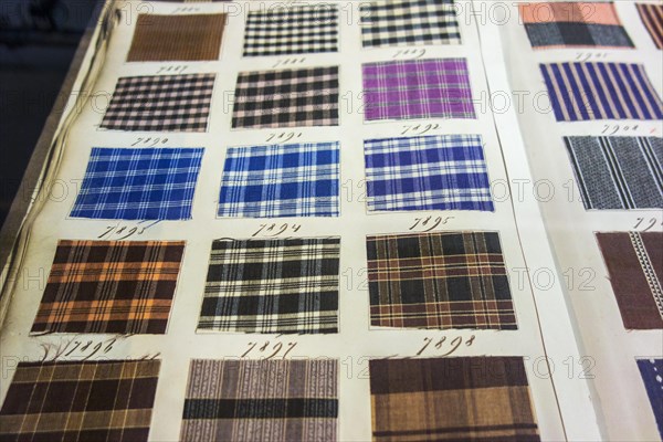 Page in old textile sample book showing chequered fabric samples with different weaving patterns and colour combinations