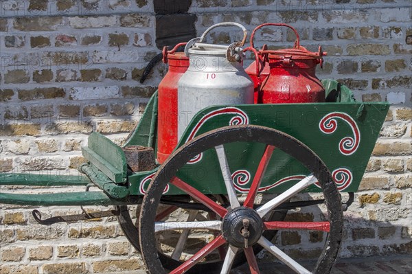 Antique handcart loaded with four old metal milk churns