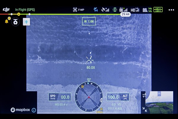 Roe deer fawn located in field on monitor with help of thermal imaging camera mounted on drone flying over meadow before mowing grassland in spring