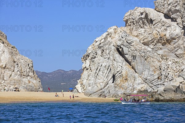 Tourist boat dropping tourists to sunbathe on secluded beach near the seaside resort Cabo San Lucas on the peninsula of Baja California Sur