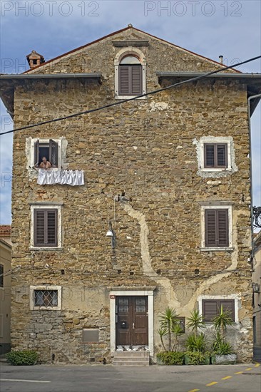 Woman in old house hanging clothes on washing line in the city Koper