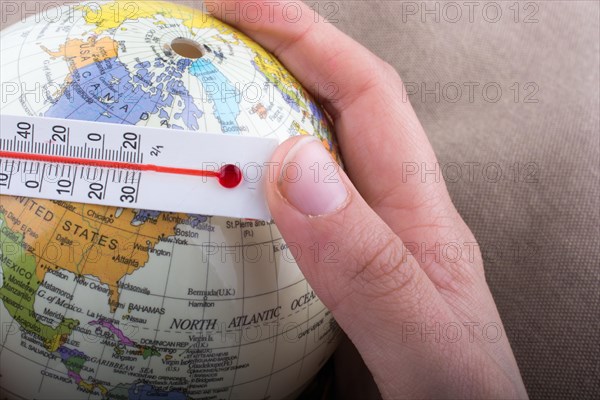 Hand placing a thermometer on a little model globe