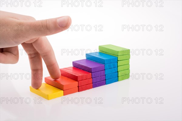 Hand playing with colored domino on white background