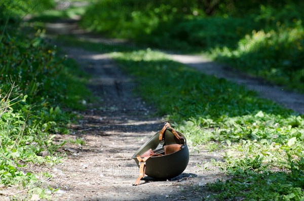 Lonely Military Helmet Lying Upside Down on a Forest Road