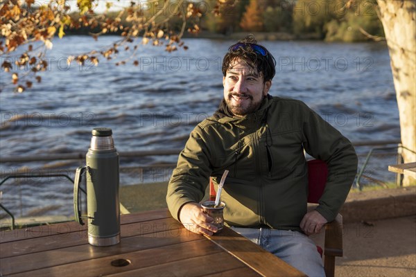 Latin man enjoying the sunset at the river while drinking mate