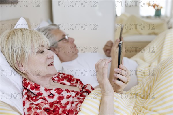 Elderly couple lying in bed together in their bedroom