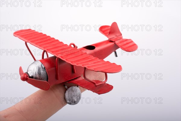 Hand holding a red toy plane on a white background