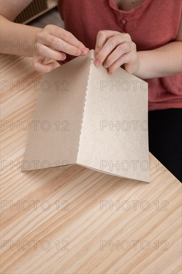 Close-up detail of woman's hands sewing a handmade notebook made in her workshop