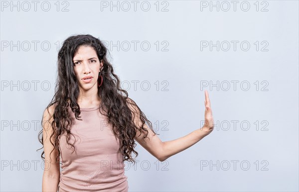 Displeased young woman rejecting with palm of hand isolated. Displeased girl making rejection gesture with palm of hand on white background