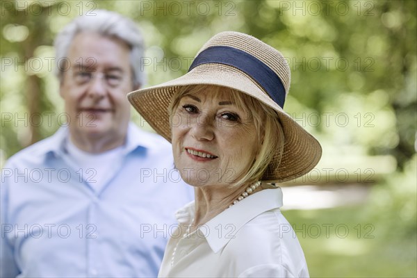 Summery dressed older woman together with her grey-haired man in the park