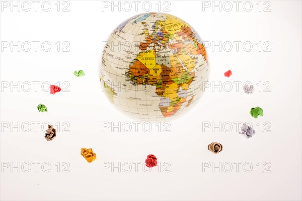 Colorful crumpled papers form a round shape around a globe on white background