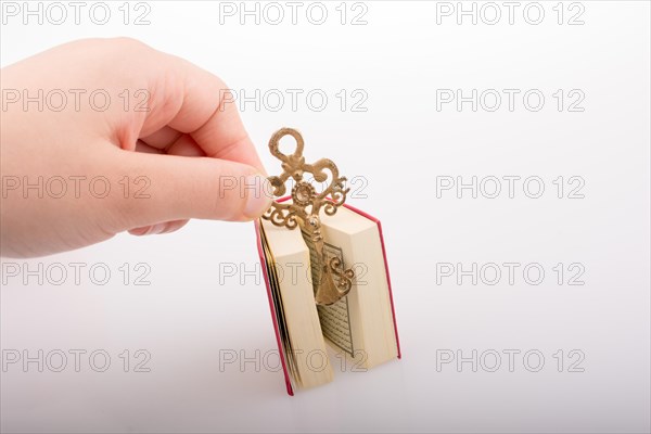 Hand holding Key and Islamic Holy Book Quran in mini size