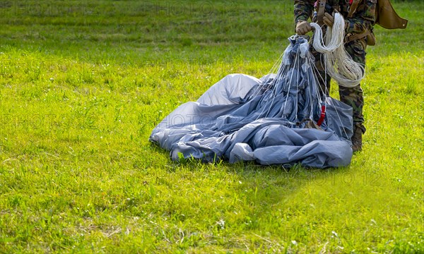 Military Parachuter Standing on the Grass with His Parachute in Switzerland